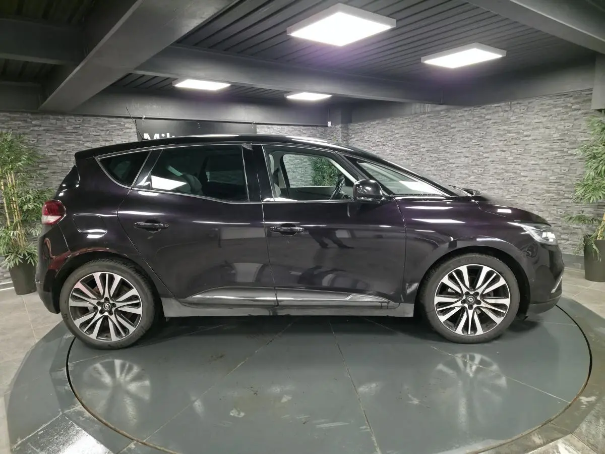 Profil droit d'un Renault Scénic noir Améthyste 2018 avec jantes alliage et toit panoramique fixe dans un showroom.