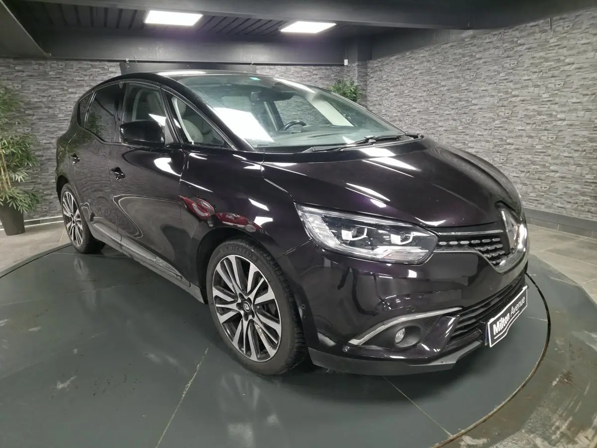 Renault Scénic noir améthyste en 3/4 avant droit, avec jantes alliage et calandre chromée Starlight visible.