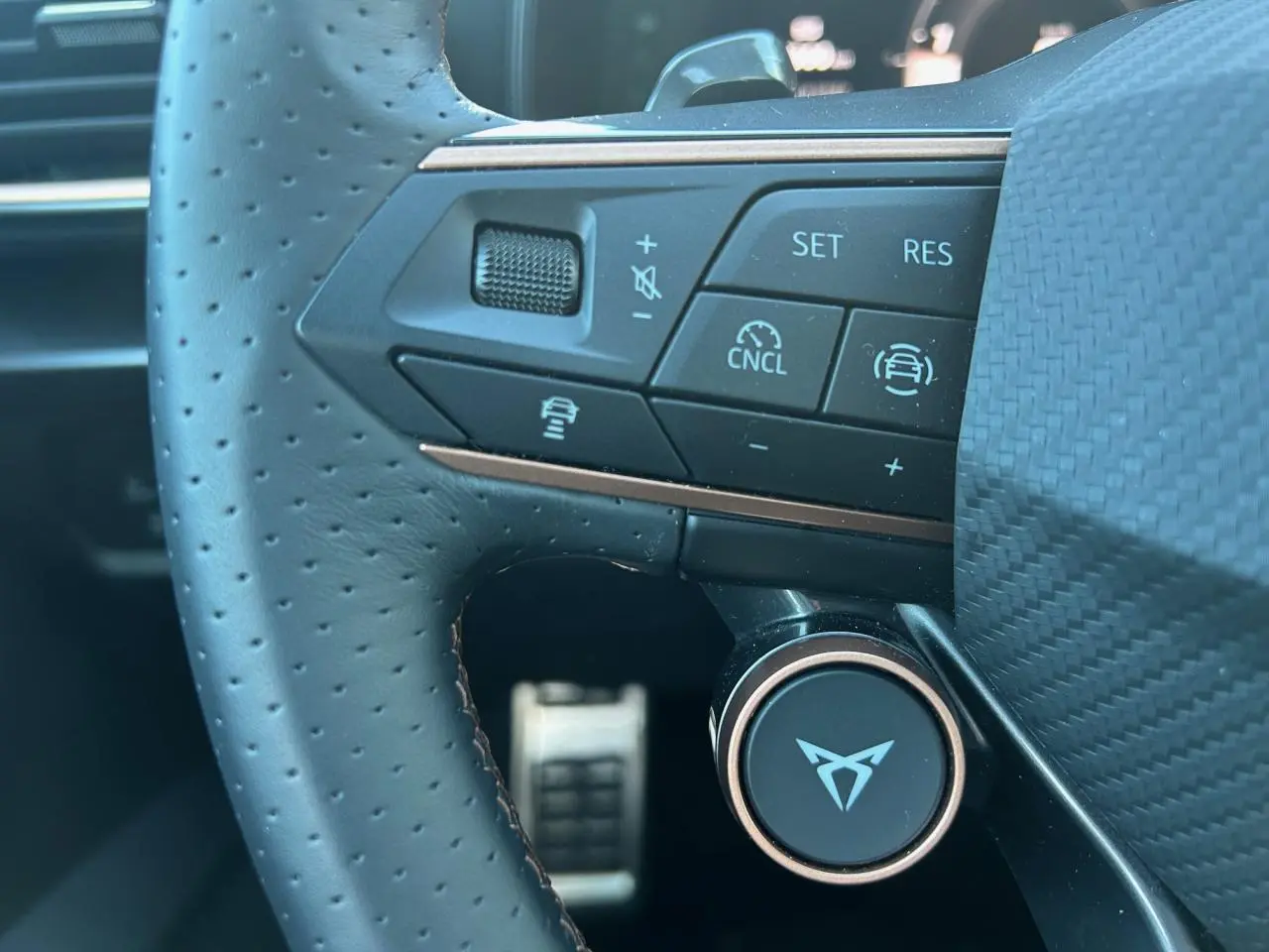 Gros plan sur le volant perforé noir du CUPRA Formentor 2025 avec commandes multifonctions et logo central distinctif.