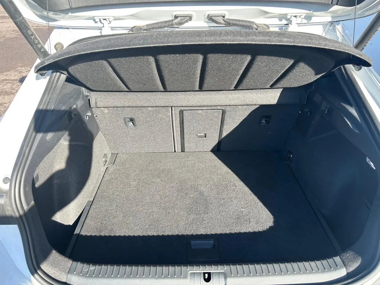 Coffre ouvert vu de l'arrière d'une CUPRA Formentor blanc neige, avec banquette arrière rabattable et cache-bagages.