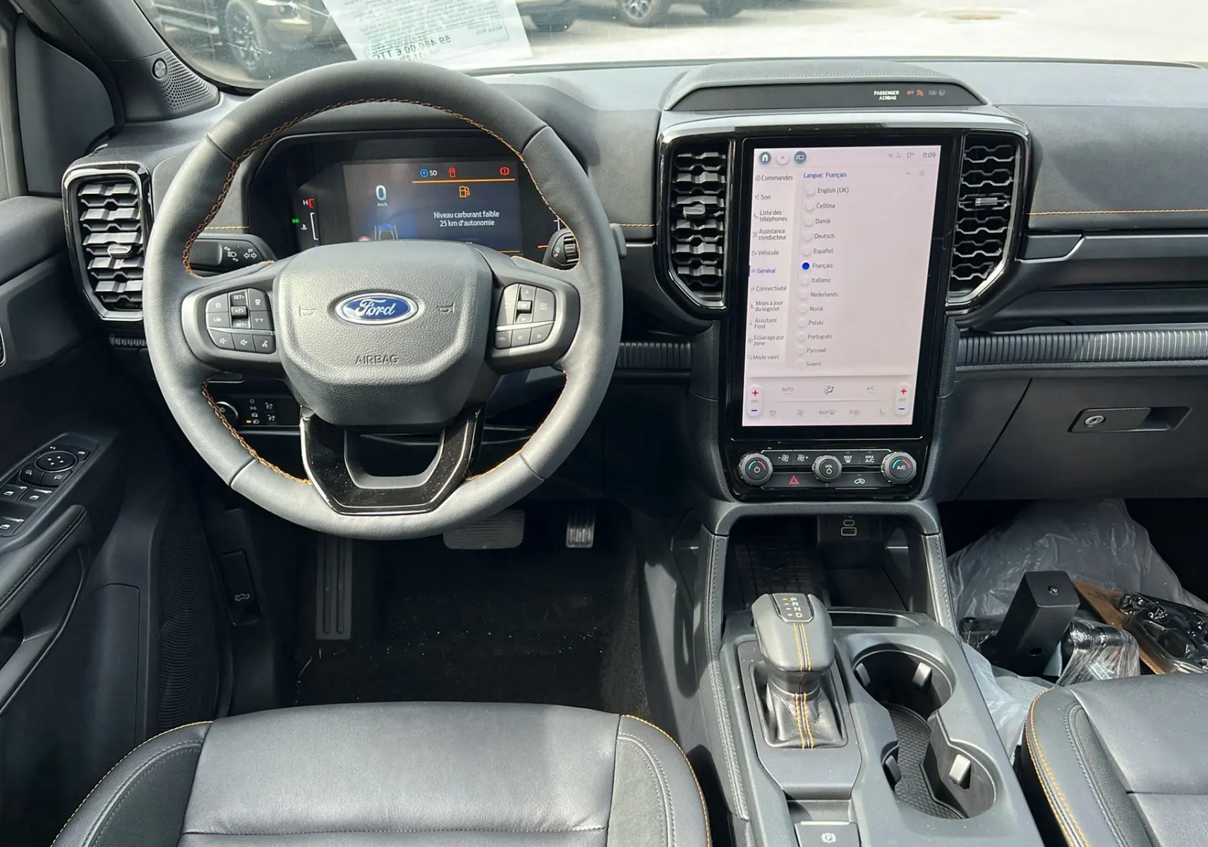 Vue intérieure avant du Ford Ranger 2026 avec volant cuir, écran tactile vertical et coutures jaunes sur levier de vitesse.