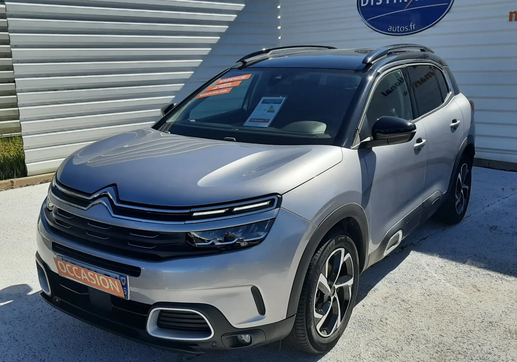 Citroën C5 Aircross gris Artense avec toit noir, vue 3/4 avant droit, jantes bi-ton et barres de toit visibles.