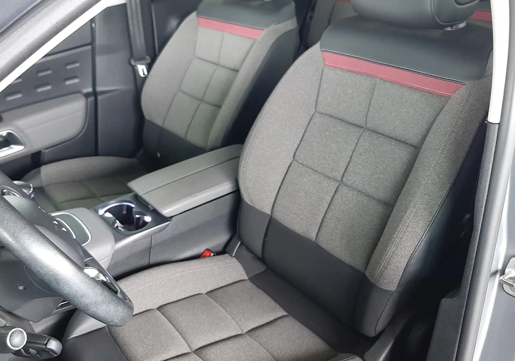 Vue intérieure côté conducteur du Citroën C5 Aircross 2021, sièges gris tissu avec bande rouge et accoudoir central.
