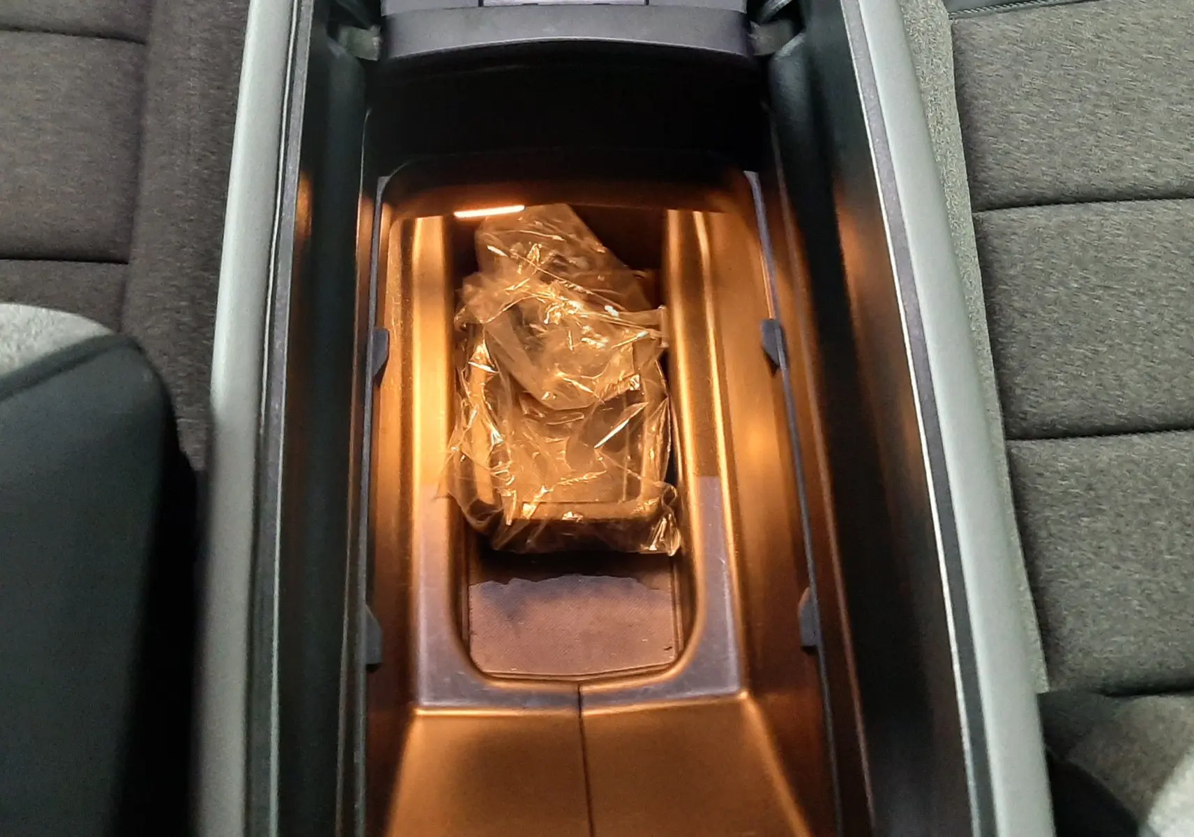 Vue plongeante sur la console centrale ouverte du Citroën C5 Aircross 1.2 PureTech 130ch, intérieur gris avec rangement éclairé.