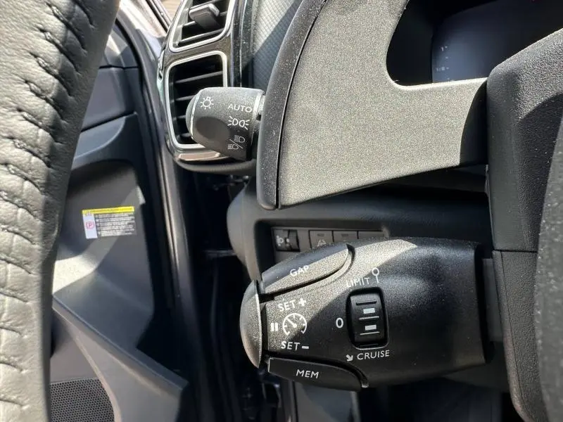 Détail du commodo de régulateur de vitesse sur le côté gauche du volant d’un Citroën C5 Aircross gris Platinium 2025.