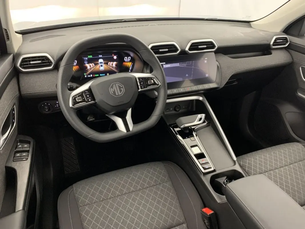Vue intérieure de face du poste de conduite du MG ZS 1.5L Hybrid+ 2026 en tissu gris avec tableau de bord numérique et écran tactile.