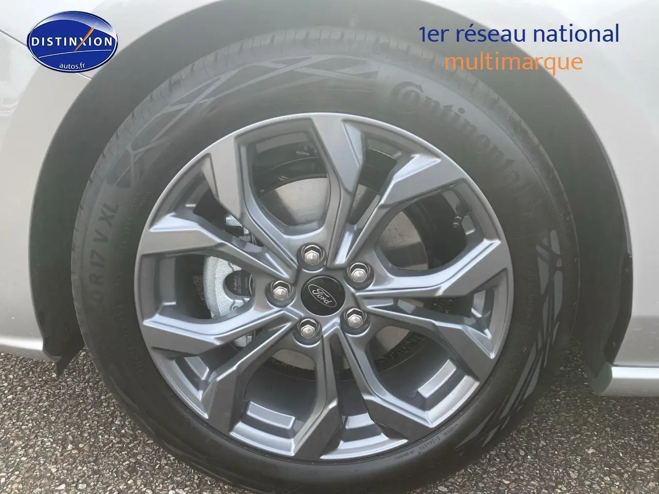 Gros plan sur la jante alu 17 pouces gris foncé d'une Ford Focus gris clair, avec logo Ford au centre.