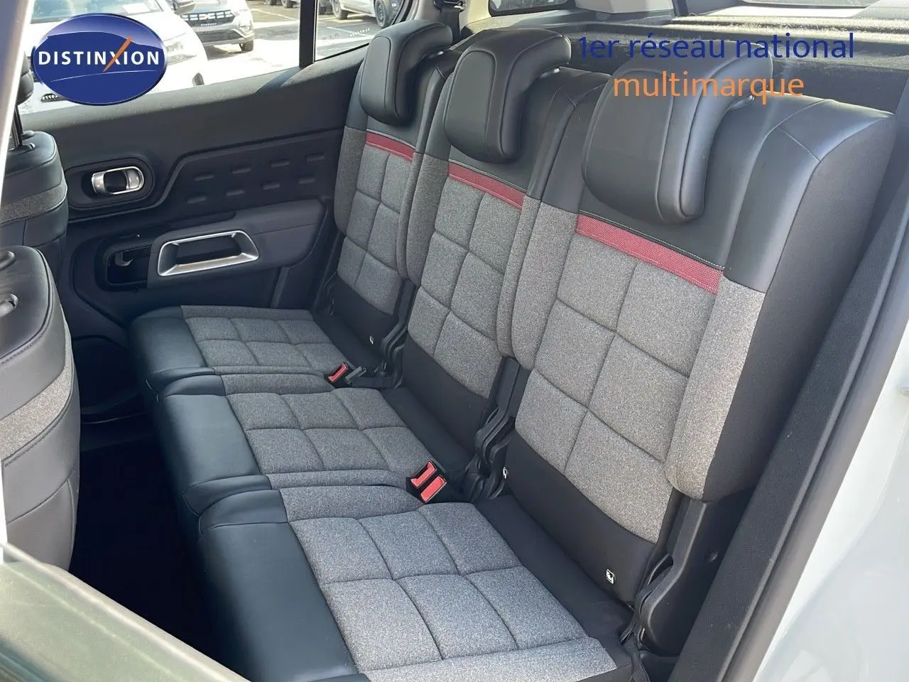Vue intérieure des sièges arrière du Citroën C5 Aircross blanc nacré, avec sellerie tissu gris et cuir noir à surpiqûres rouges.