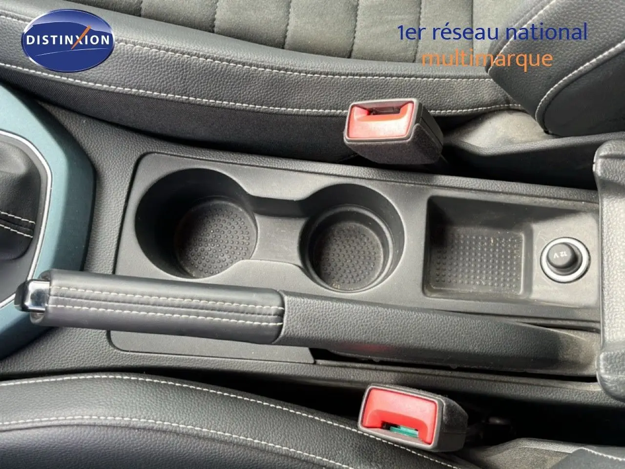 Vue plongeante sur la console centrale du SEAT Arona 2025 gris falaise, avec frein à main et porte-gobelets visibles.