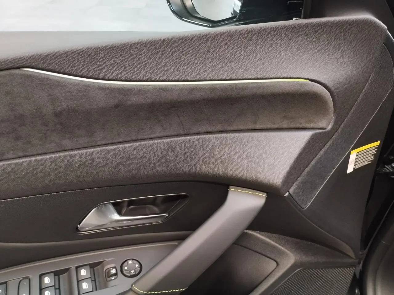 Détail de la porte avant gauche de la Peugeot 308 noire, avec surpiqûres vert Adamite et insert alcantara.