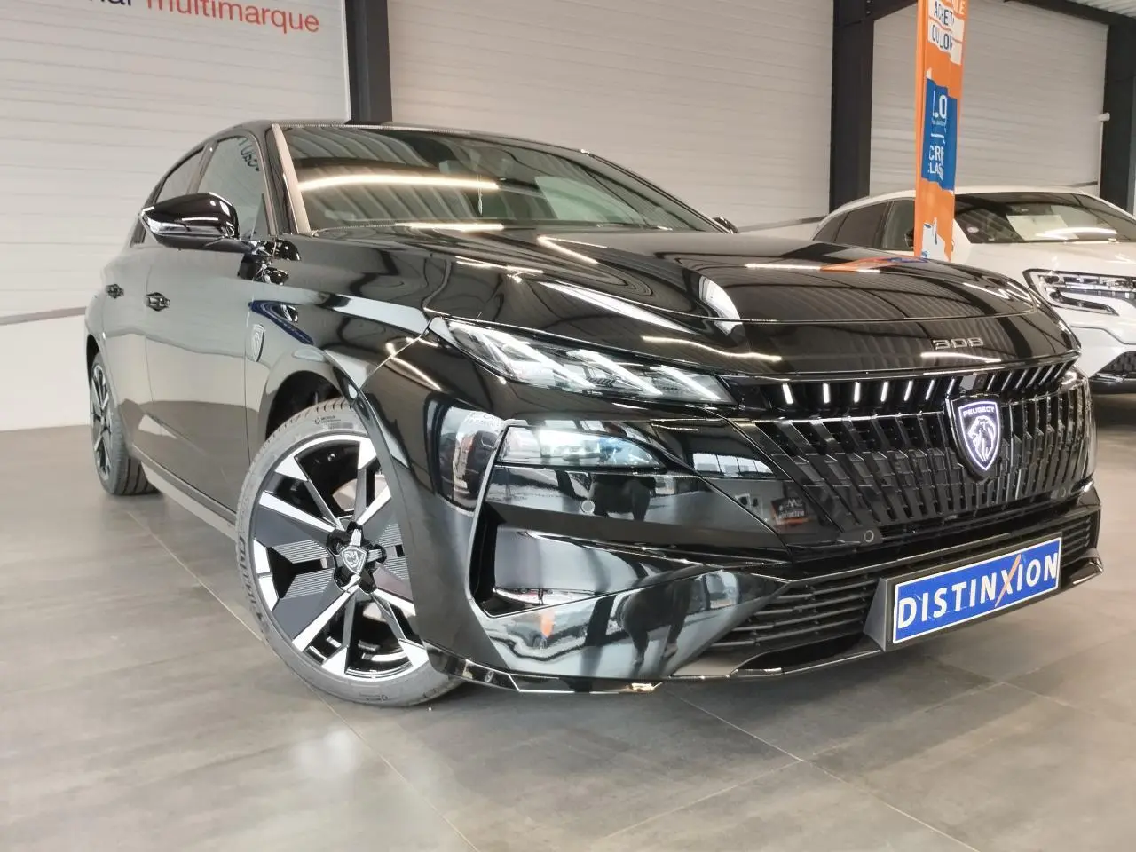 Peugeot 308 noir métallisé vue 3/4 avant avec calandre illuminée et jantes alliage bi-tons.
