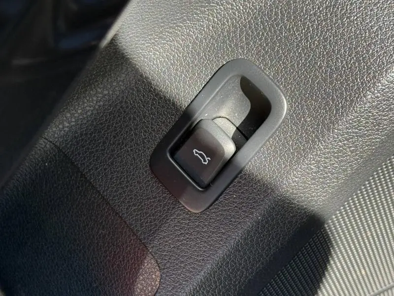 Détail du bouton d'ouverture du coffre sur la garniture intérieure d'un Audi Q2 35 TDI 150ch S line 2025 gris Daytona nacré.