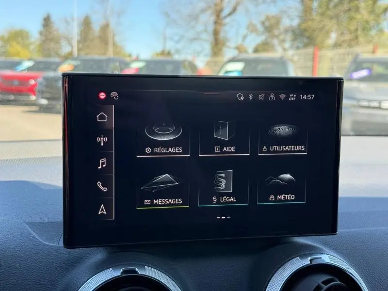 Écran tactile central de l'Audi Q2 35 TDI S line 2025, affichant le menu des réglages dans un intérieur gris.
