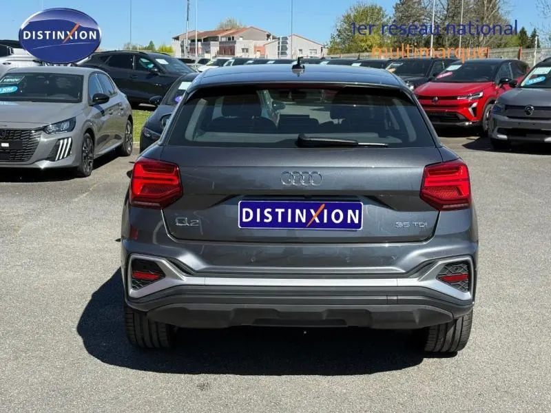 Vue arrière d'un Audi Q2 35 TDI S line gris Daytona nacré, mettant en valeur ses feux rouges et son logo distinctif.