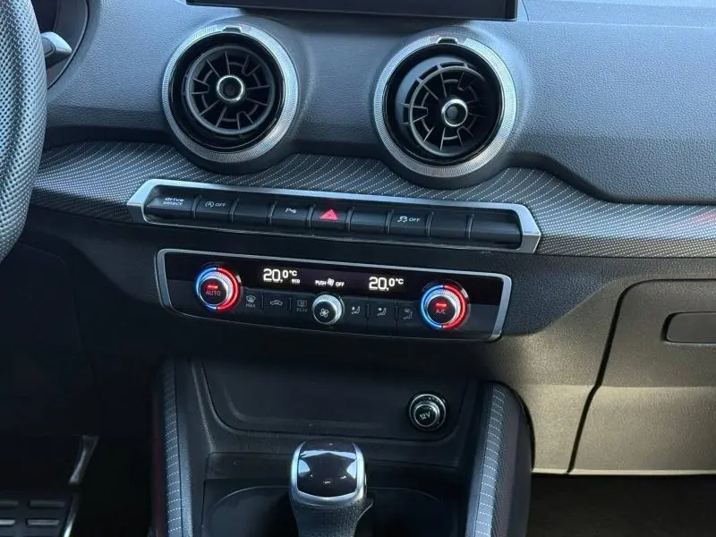 Détail de la console centrale de l'Audi Q2 35 TDI 150ch S line 2025, montrant les aérateurs ronds et les commandes climatisation.