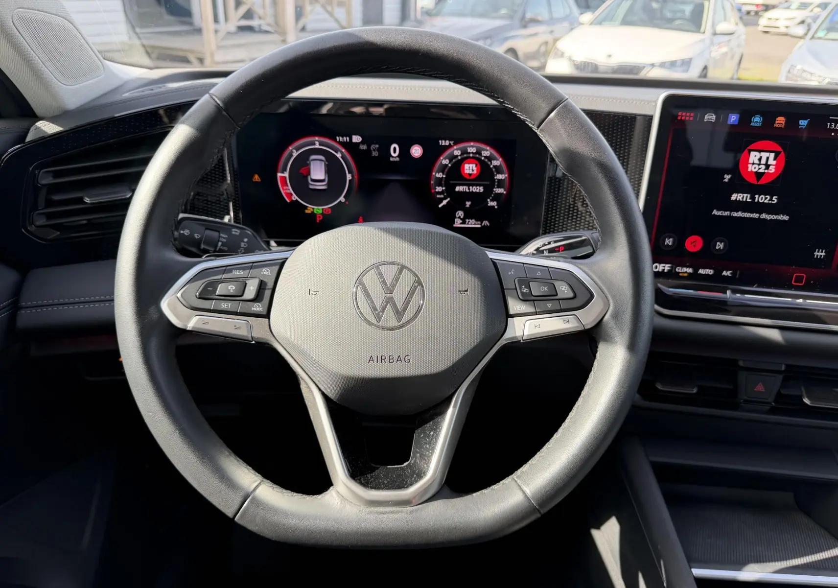 Vue intérieure centrée sur le volant cuir noir du Volkswagen Tiguan 2025 avec tableau de bord digital et écran tactile.