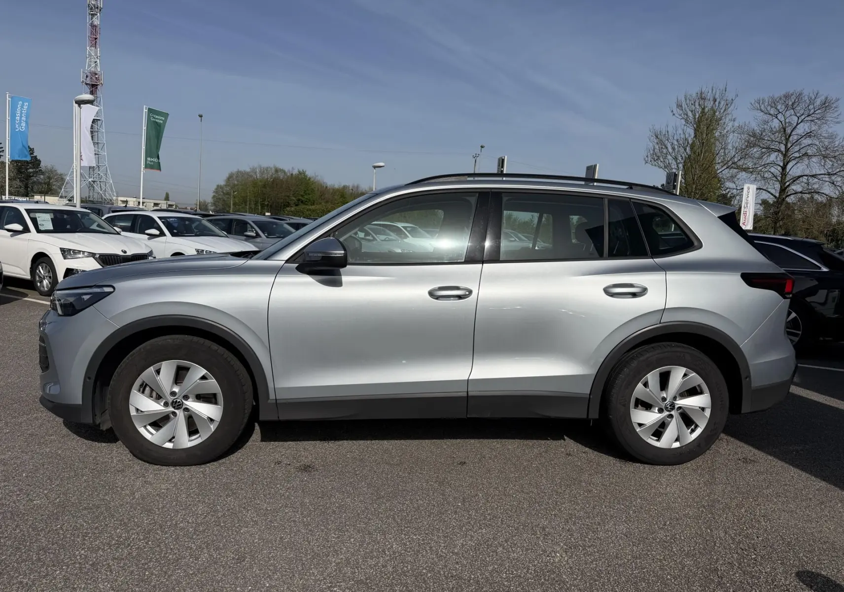 Profil droit d’un Volkswagen Tiguan gris 2025, avec jantes alliage 17 pouces et barres de toit noires.