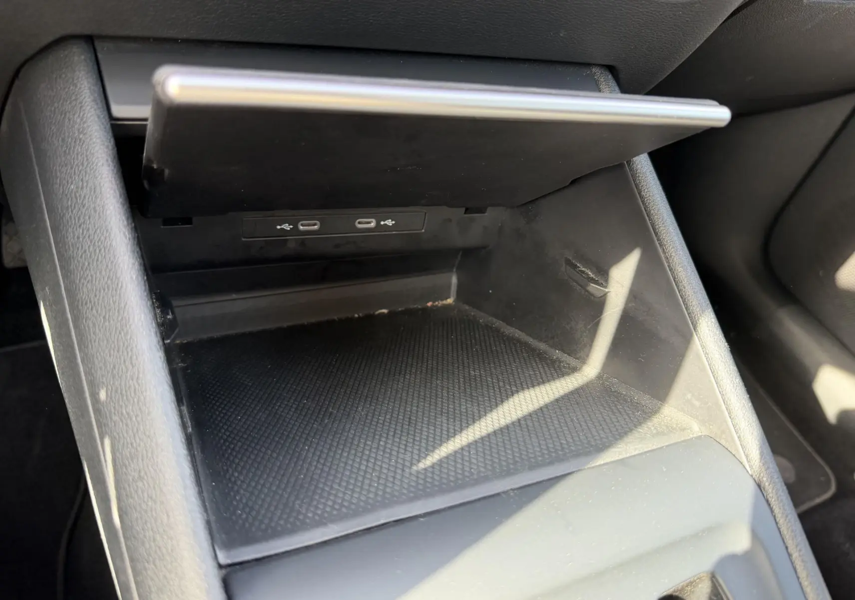 Rangement central ouvert avec deux ports USB-C visibles dans l'habitacle noir du Volkswagen Tiguan gris.
