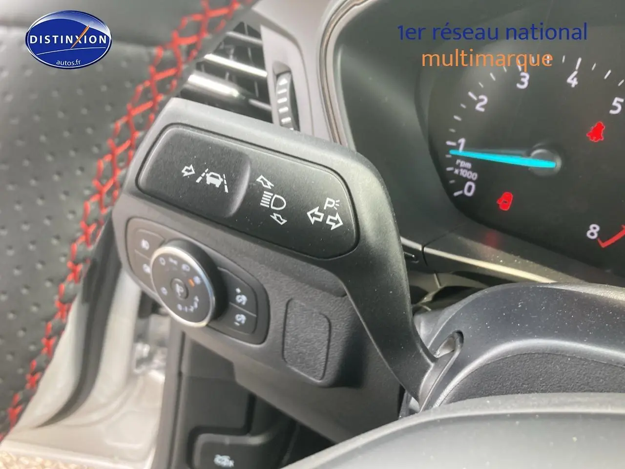 Gros plan sur la manette de clignotants et volant avec surpiqûres rouges de la Ford Focus gris 2025.