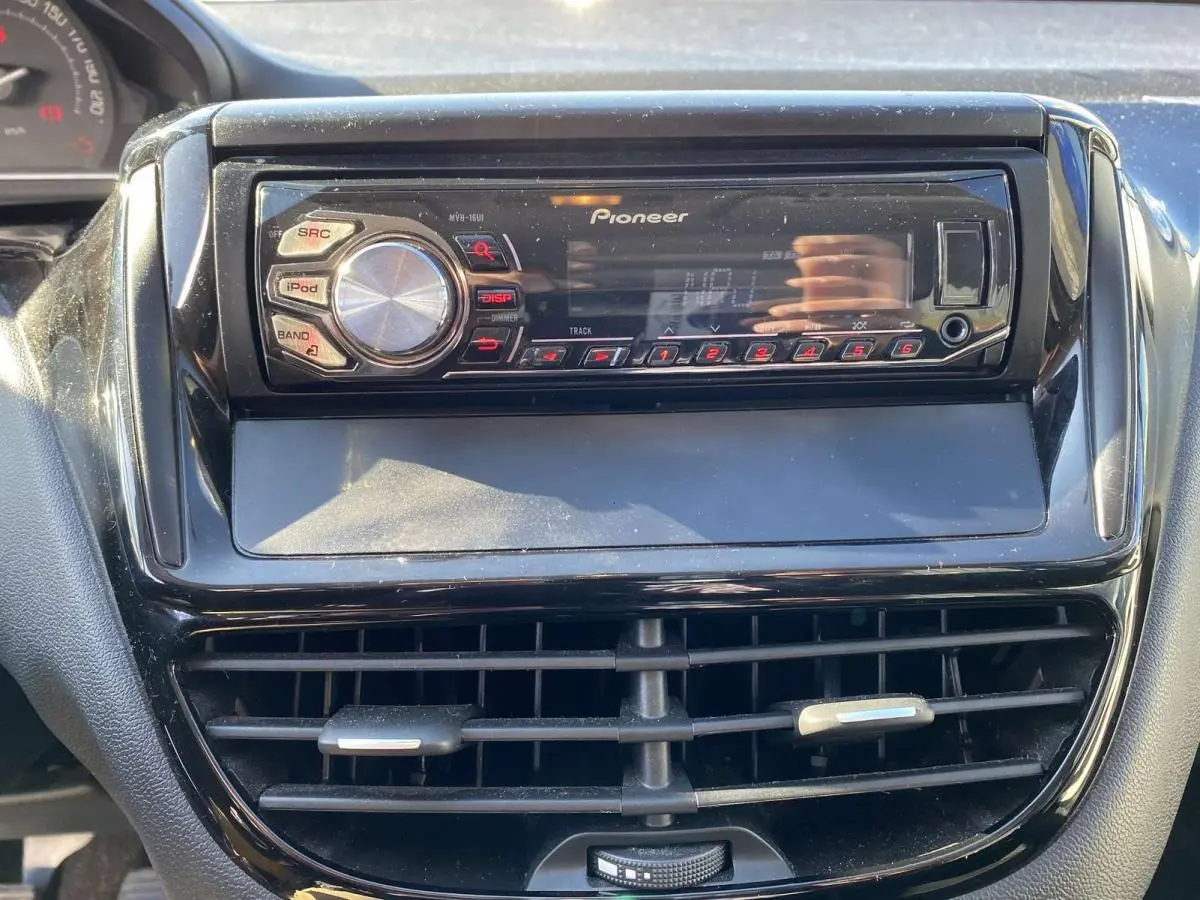 Autoradio Pioneer intégré au tableau de bord noir du Peugeot 208 2015, avec commandes et écran digital visibles.