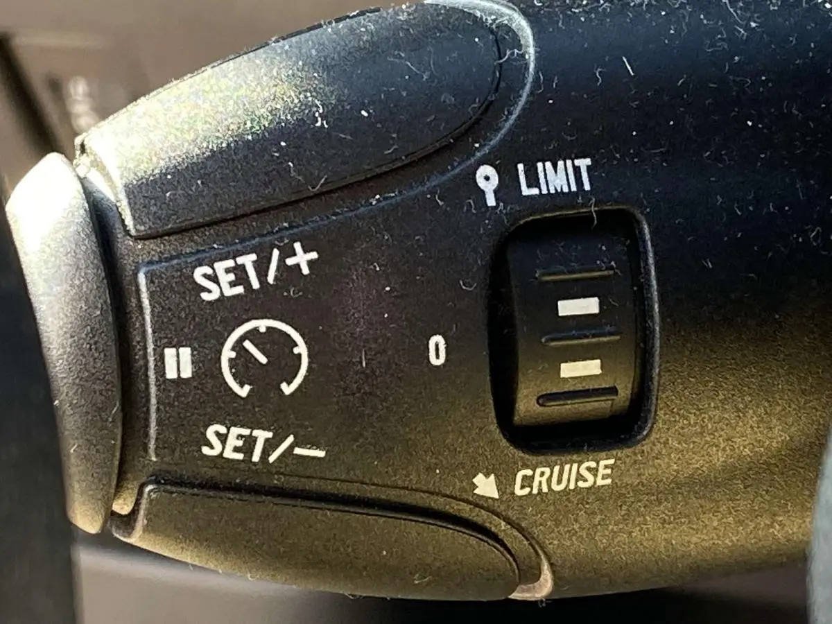 Gros plan sur la commande de régulateur de vitesse du Peugeot 208 noir, avec boutons SET, LIMIT et CRUISE visibles.
