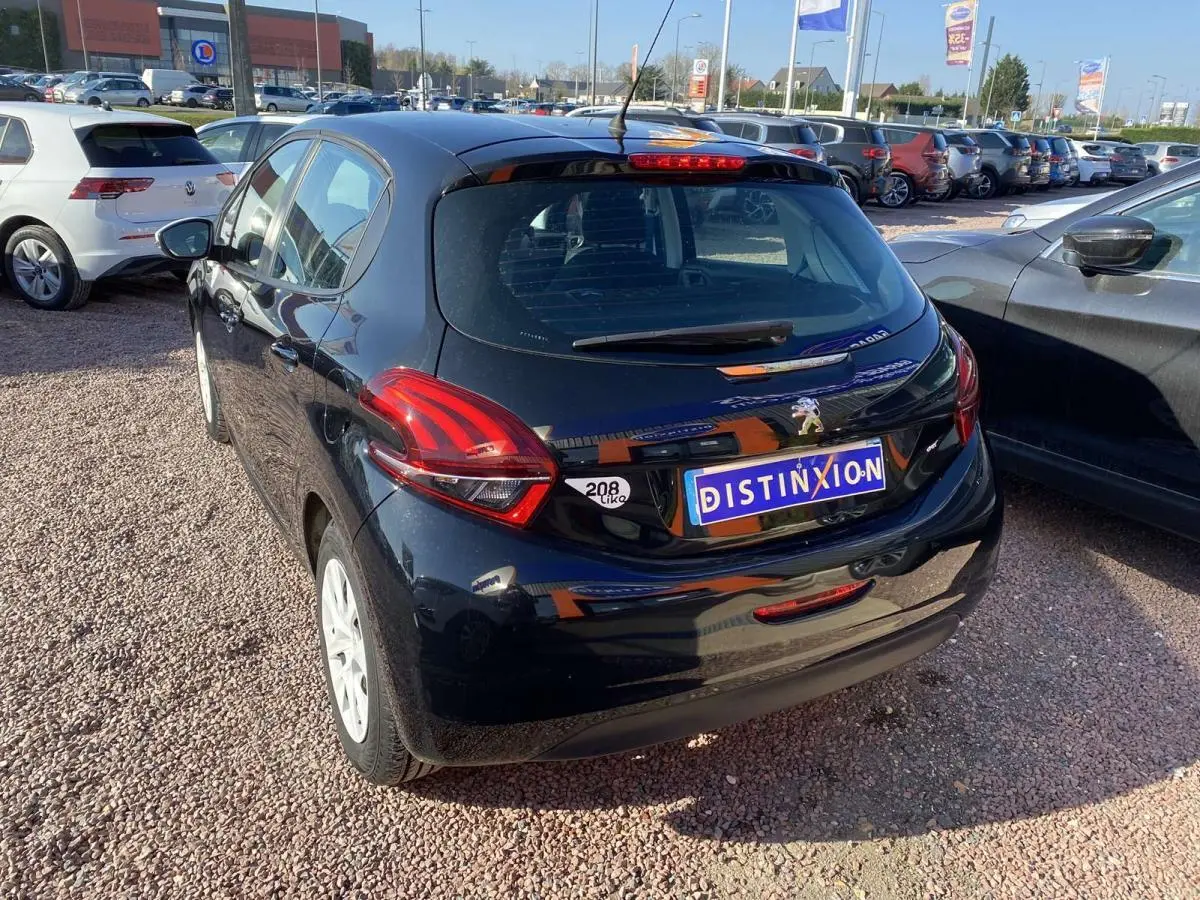 Peugeot 208 noire vue en 3/4 arrière droit, avec jantes blanches et plaque Distinxion visible.