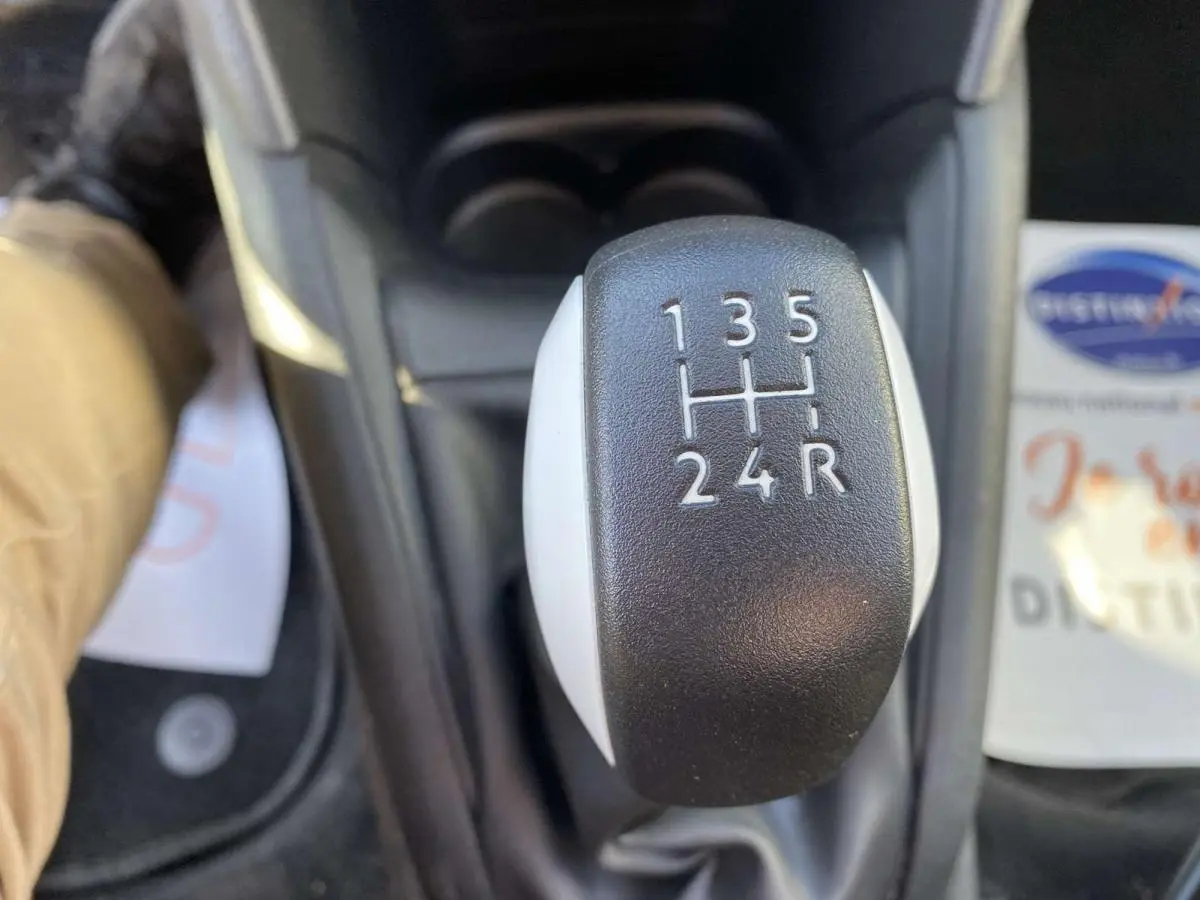 Le levier de vitesses manuel noir et blanc de la Peugeot 208 essence, vue en gros plan depuis l'intérieur.