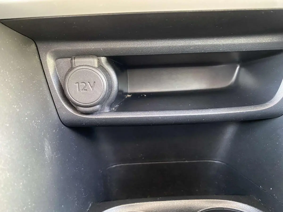 Prise 12V en gros plan dans la console centrale d'une Peugeot 208 noire essence de 2015.