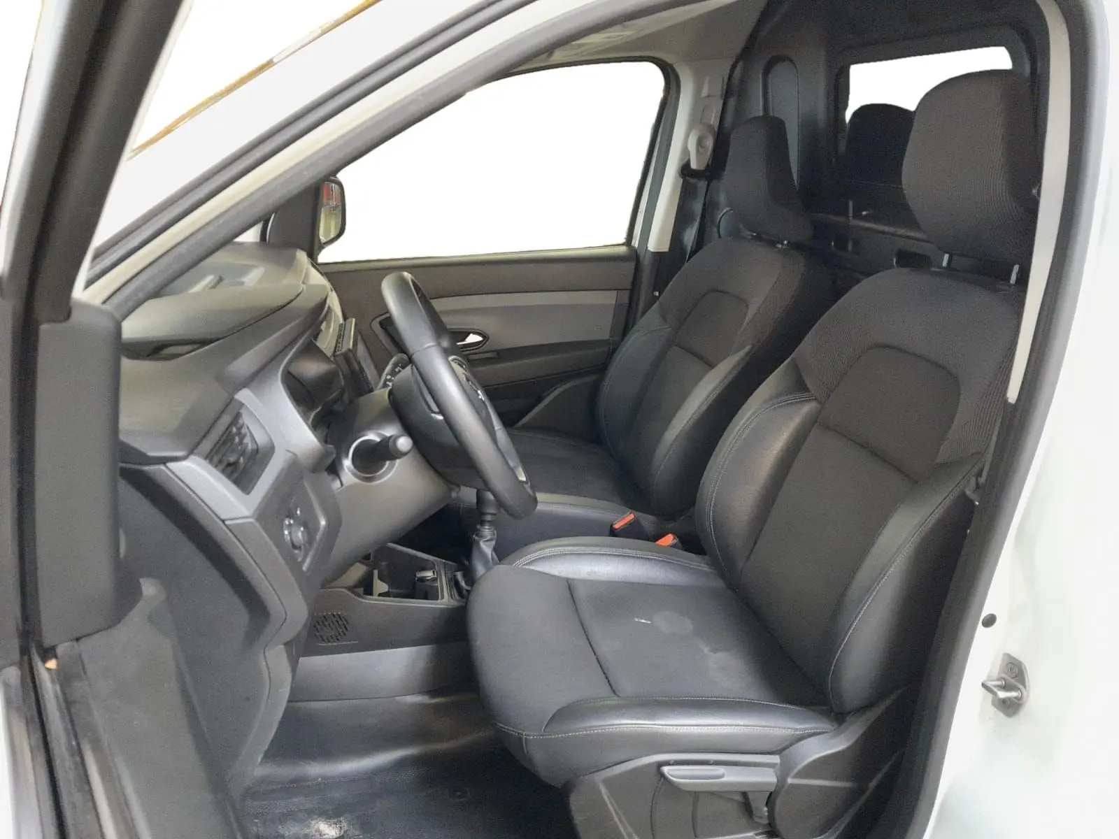 Intérieur du Renault Express Van blanc 2023, vue côté conducteur, sièges noirs en tissu et tableau de bord simple.