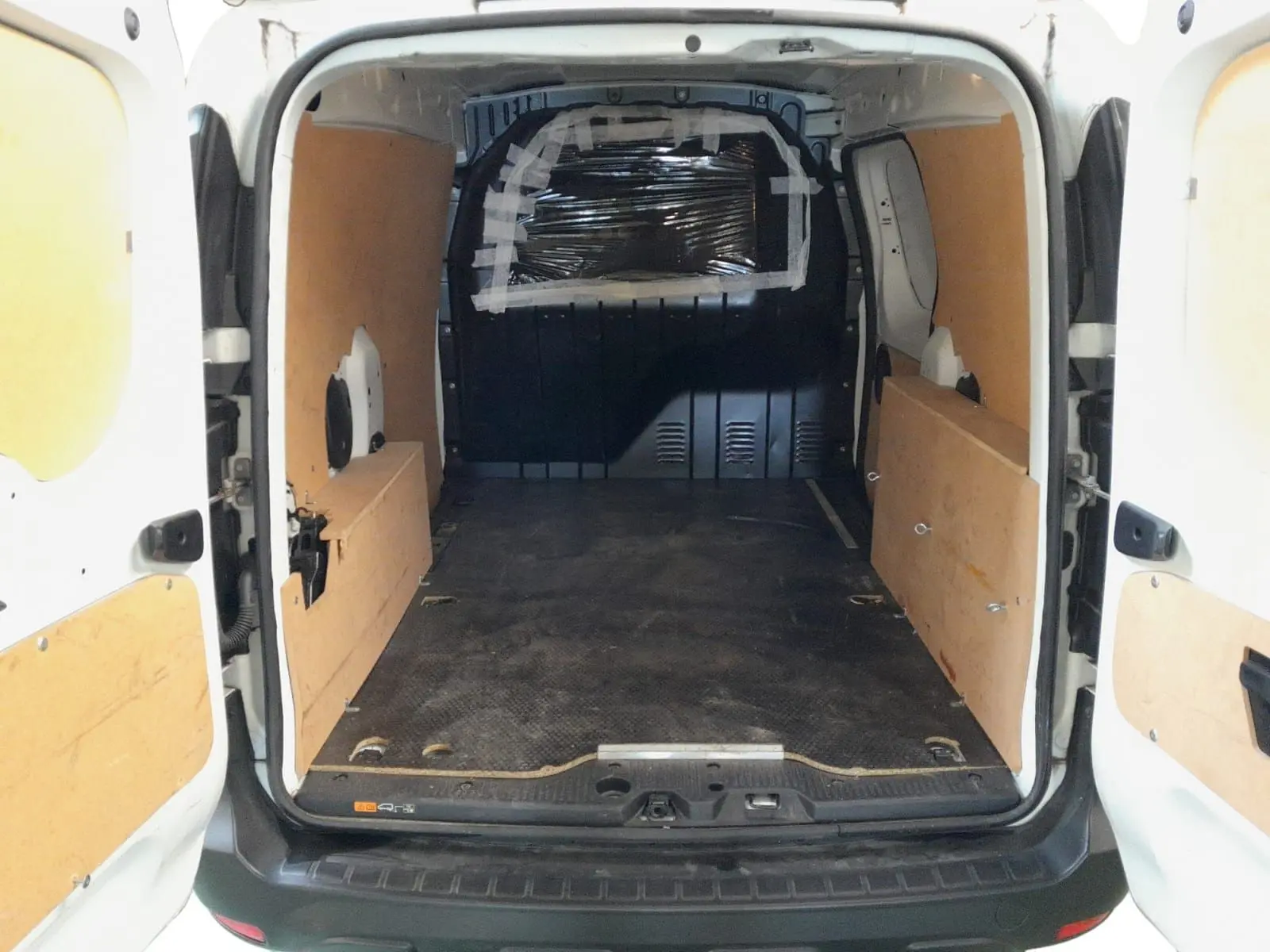 Vue arrière intérieure du Renault Express Van blanc 2023, montrant l'espace de chargement avec panneaux en bois et sol noir antidérapant.