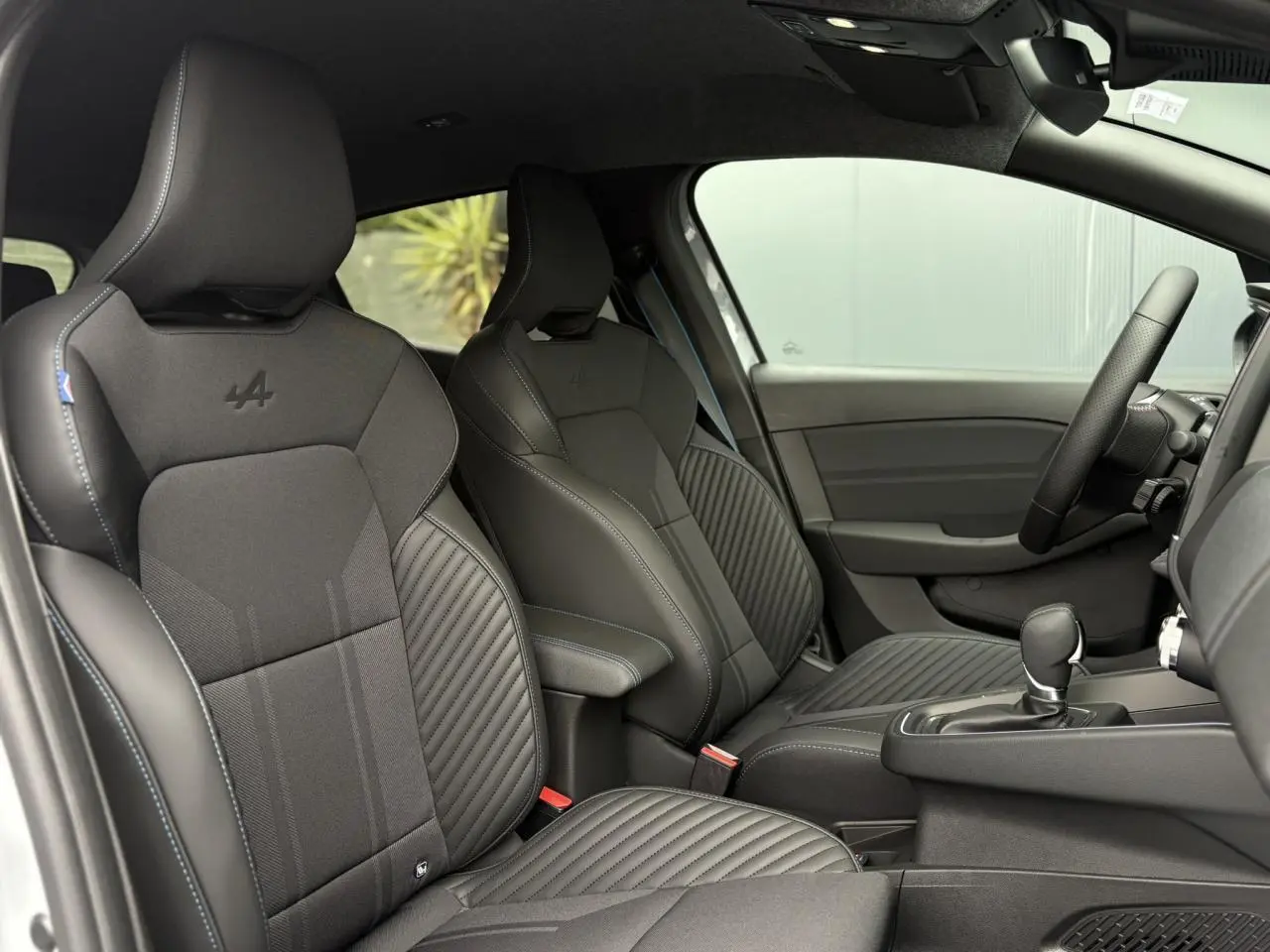 Vue intérieure côté droit des sièges sport noirs avec surpiqûres bleues et logo Alpine sur Renault Clio Esprit Alpine 2025