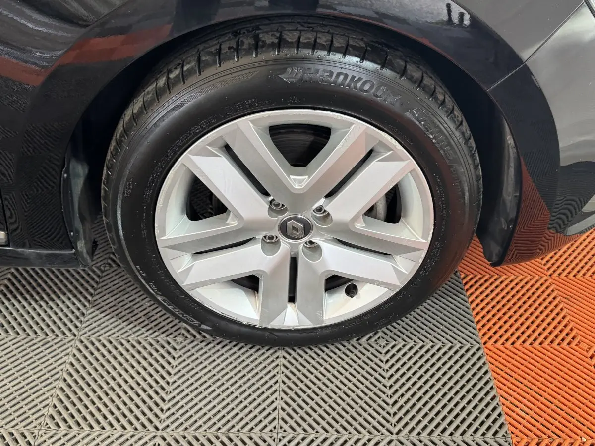 Gros plan sur la roue avant droite d'une Renault Clio Business E-Tech noire, avec jante alliage argentée et pneu Hankook.