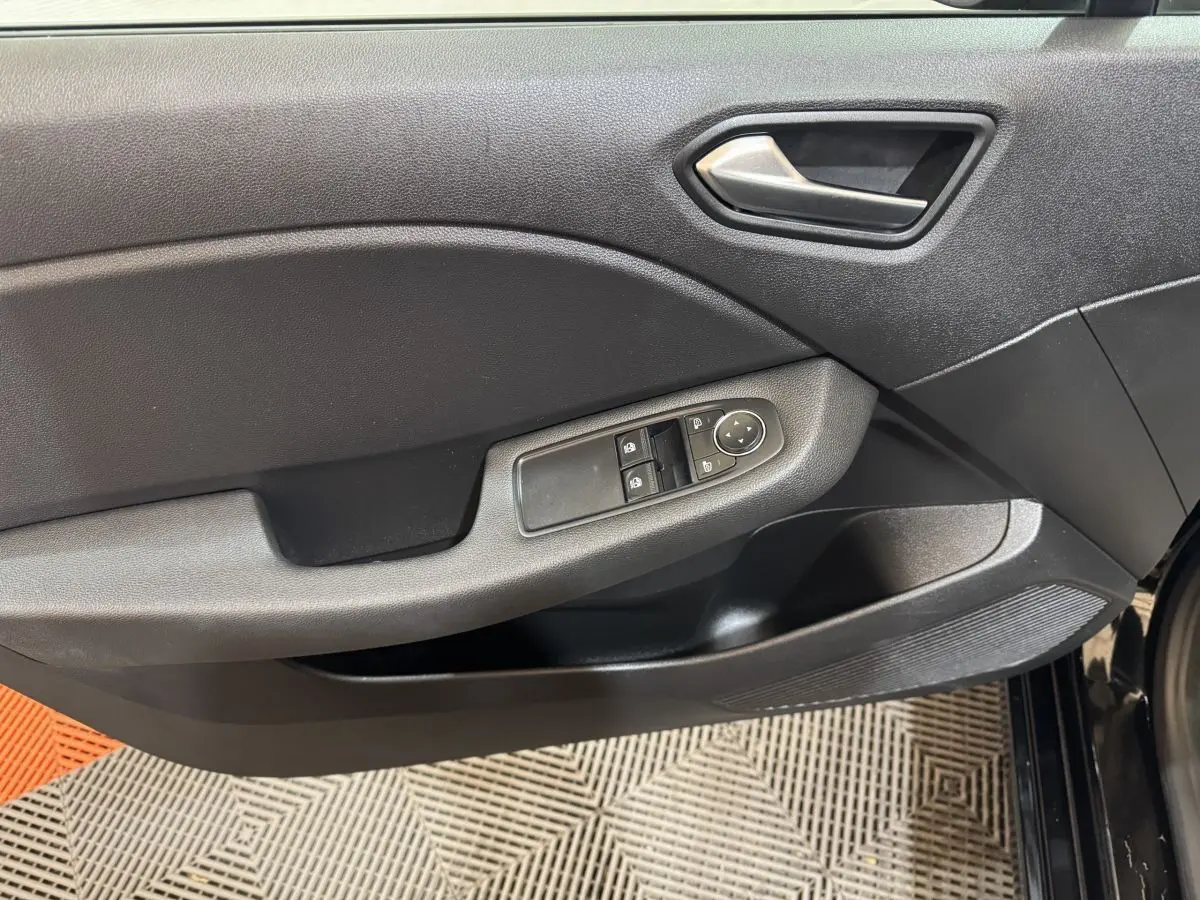 Vue rapprochée de la porte intérieure côté gauche de la Renault Clio Business E-Tech noire, avec commandes électriques des vitres.