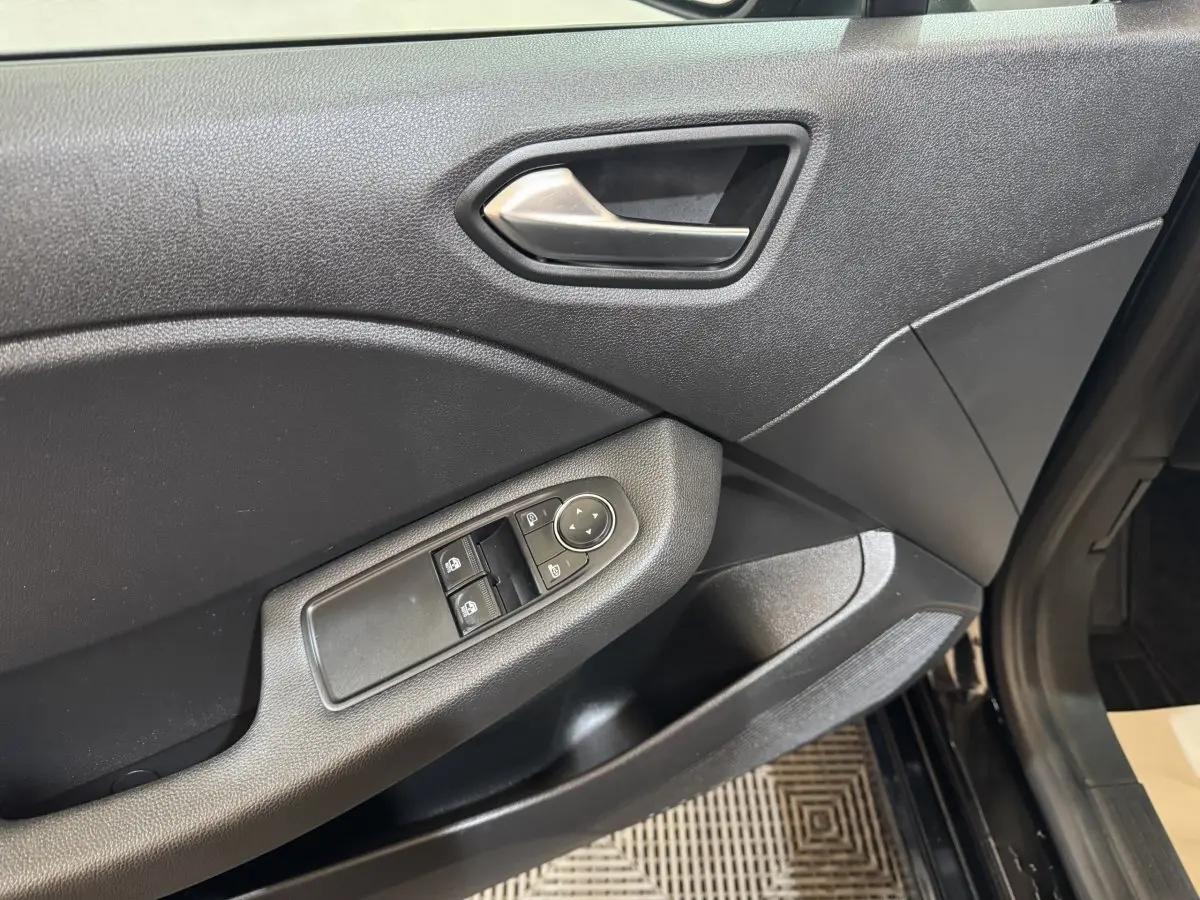 Vue rapprochée de la porte avant gauche noire de la Renault Clio Business E-Tech hybride avec commandes électriques des vitres.