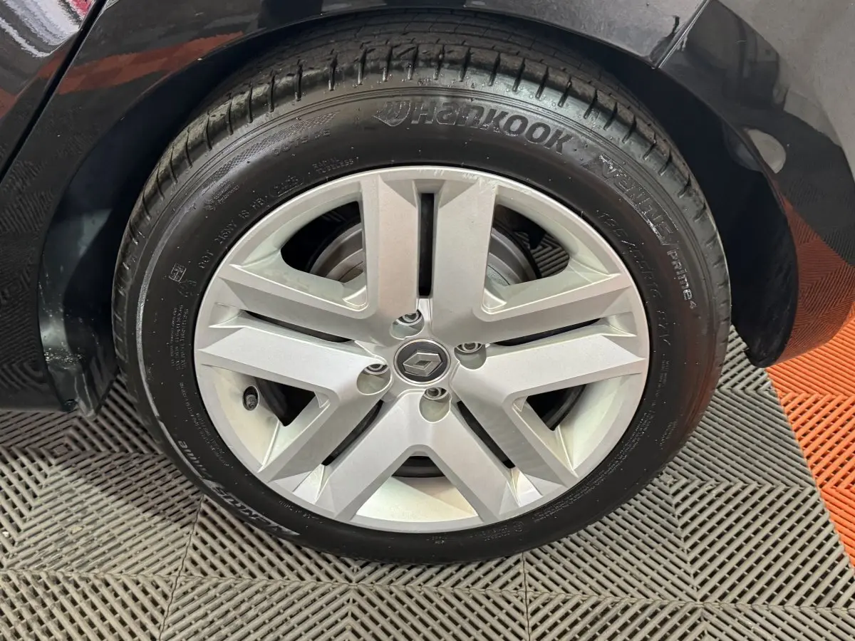 Gros plan sur la roue avant droite noire d’une Renault Clio Business E-Tech hybride 2021 avec jante argentée à cinq branches.