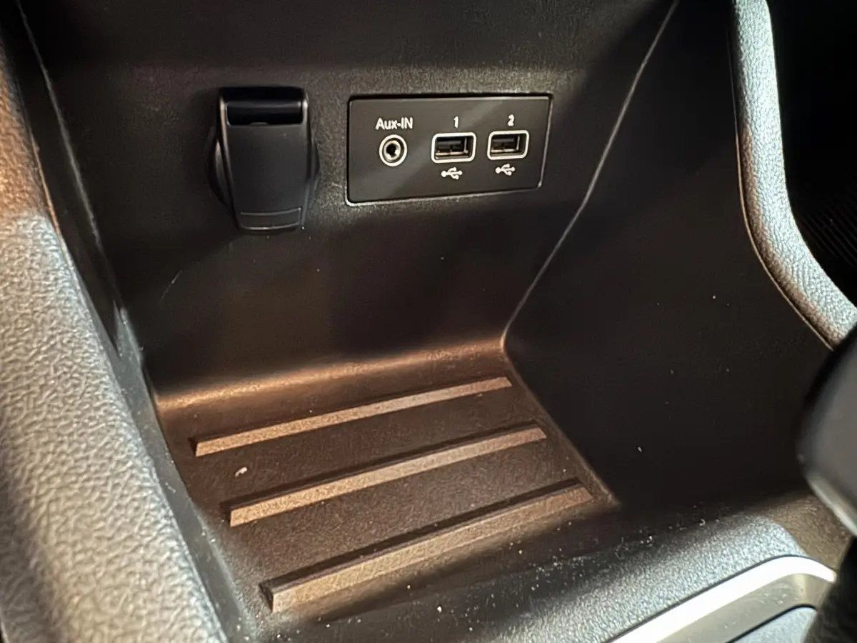 Gros plan sur la console centrale noire de la Renault Clio Business E-Tech hybride avec ports USB et prise Aux-IN.