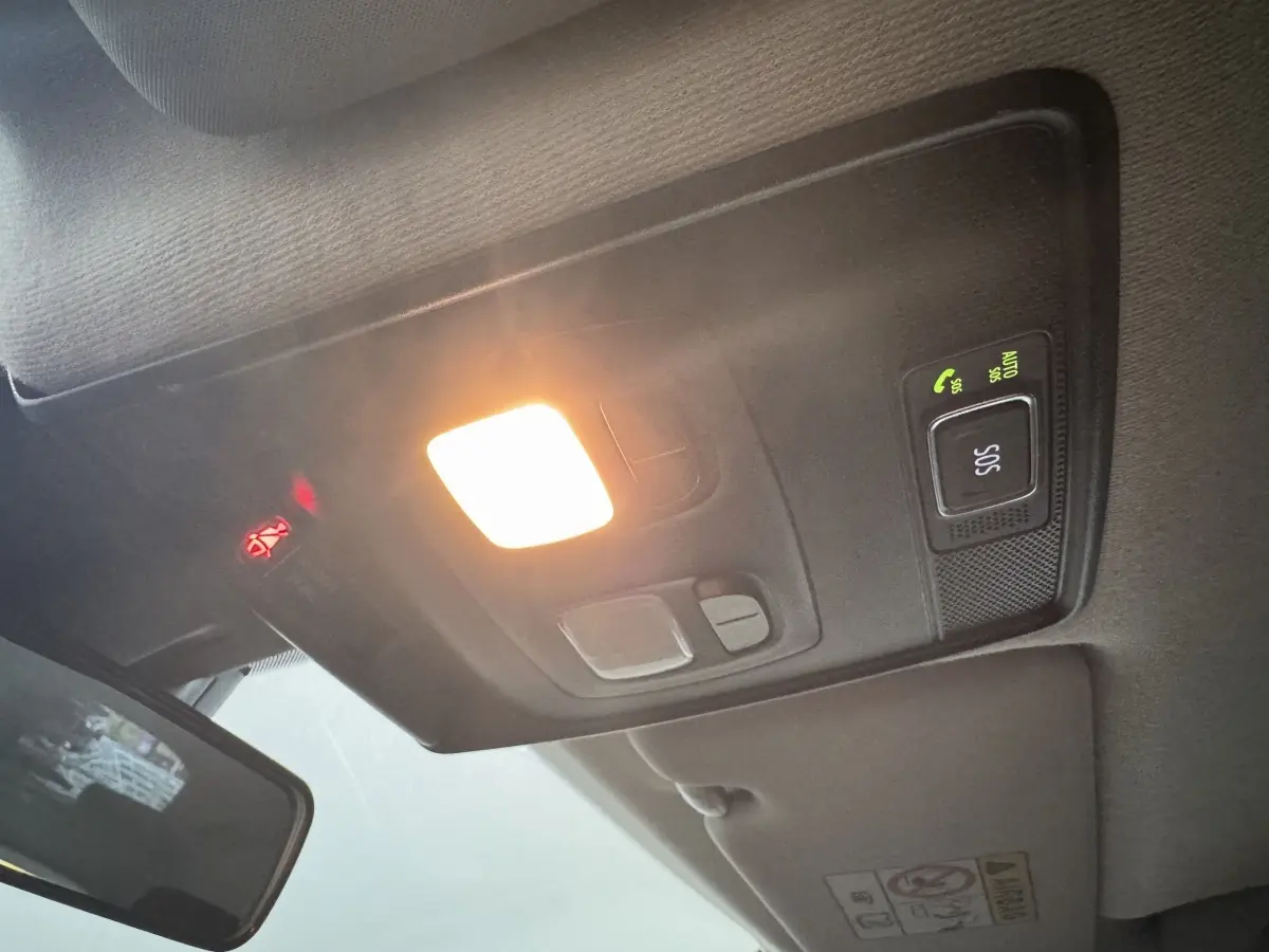 Plafonnier allumé avec bouton SOS et témoin de ceinture, vue intérieure avant d'une Renault Clio noire hybride.
