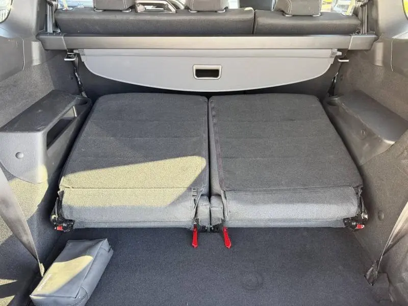 Vue du coffre arrière du Dacia Jogger 2025 gris Schiste métallisé avec sièges rabattus et cache-bagages déployé.
