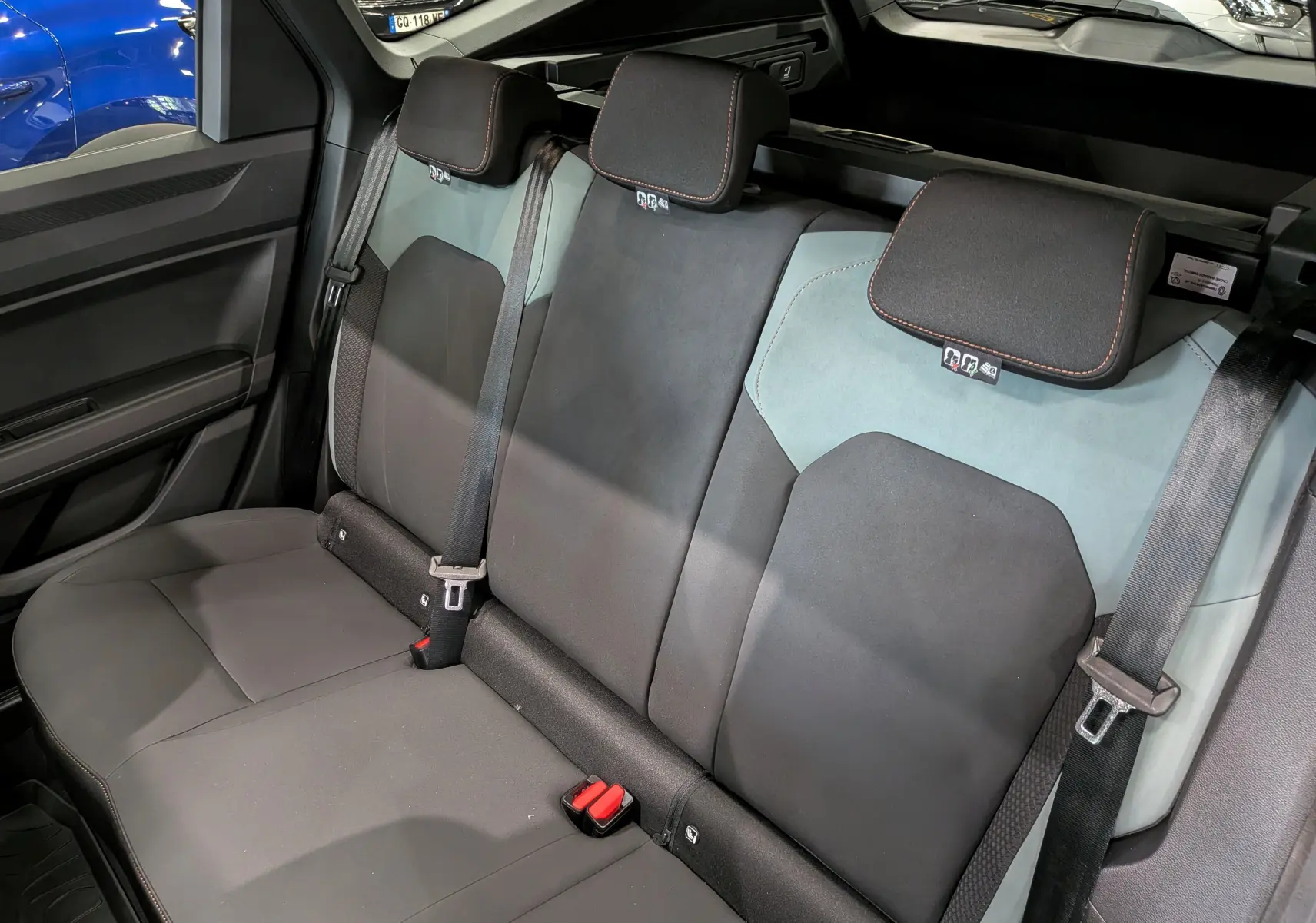 Vue intérieure sur la banquette arrière du Dacia Bigster Hybrid-G 150 4x4, sièges bicolores gris et noir avec ceintures.