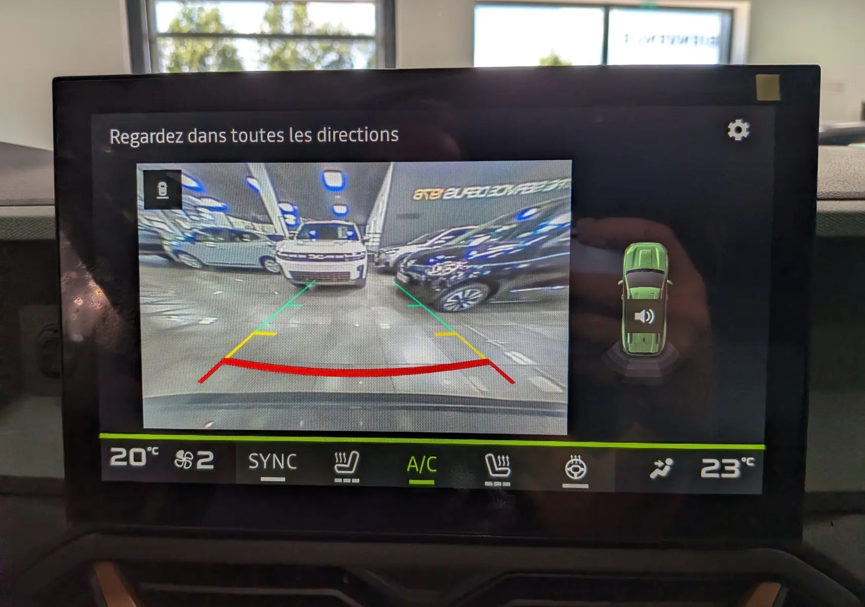 Vue caméra de recul montrant une Dacia Bigster gris schiste de face dans un parking intérieur.