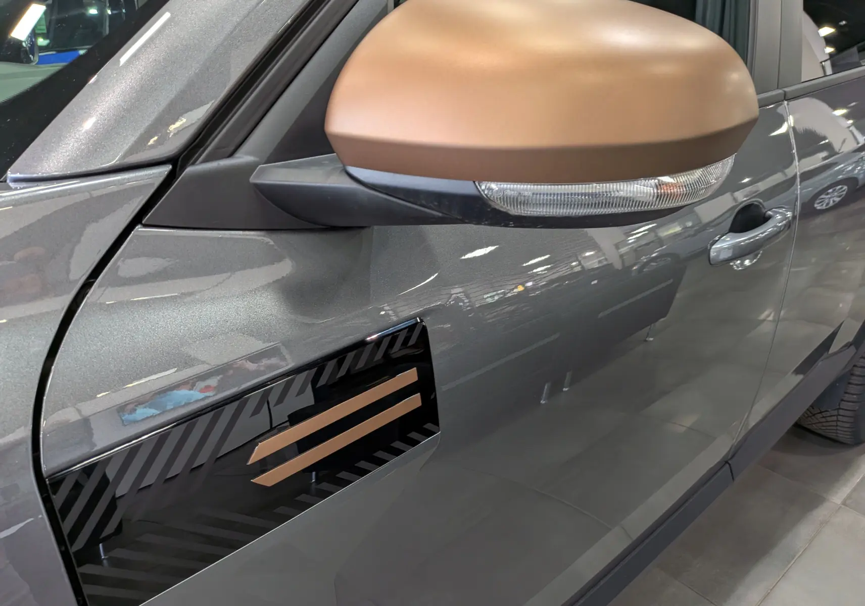 Gros plan sur le rétroviseur bronze et la portière gris schiste du Dacia Bigster Hybrid-G 150 4x4 Extrême côté gauche.