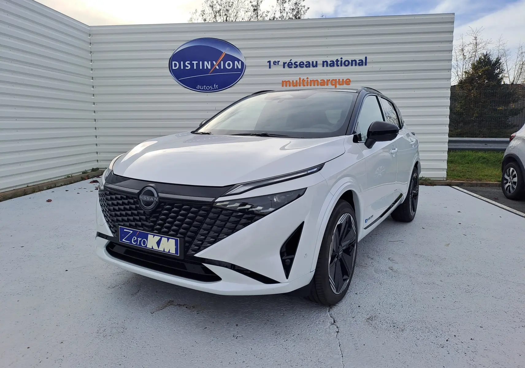 Nissan Qashqai blanc nacré avec toit noir, vue 3/4 avant droit, calandre noire et jantes stylisées.