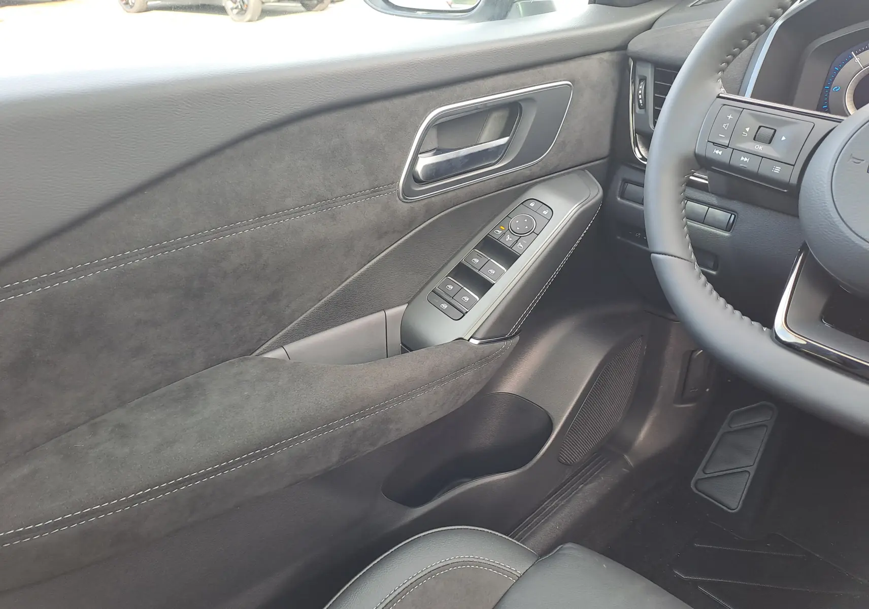 Détail de la porte côté conducteur en tissu noir avec commandes électriques sur Nissan Qashqai blanc nacré 2025.