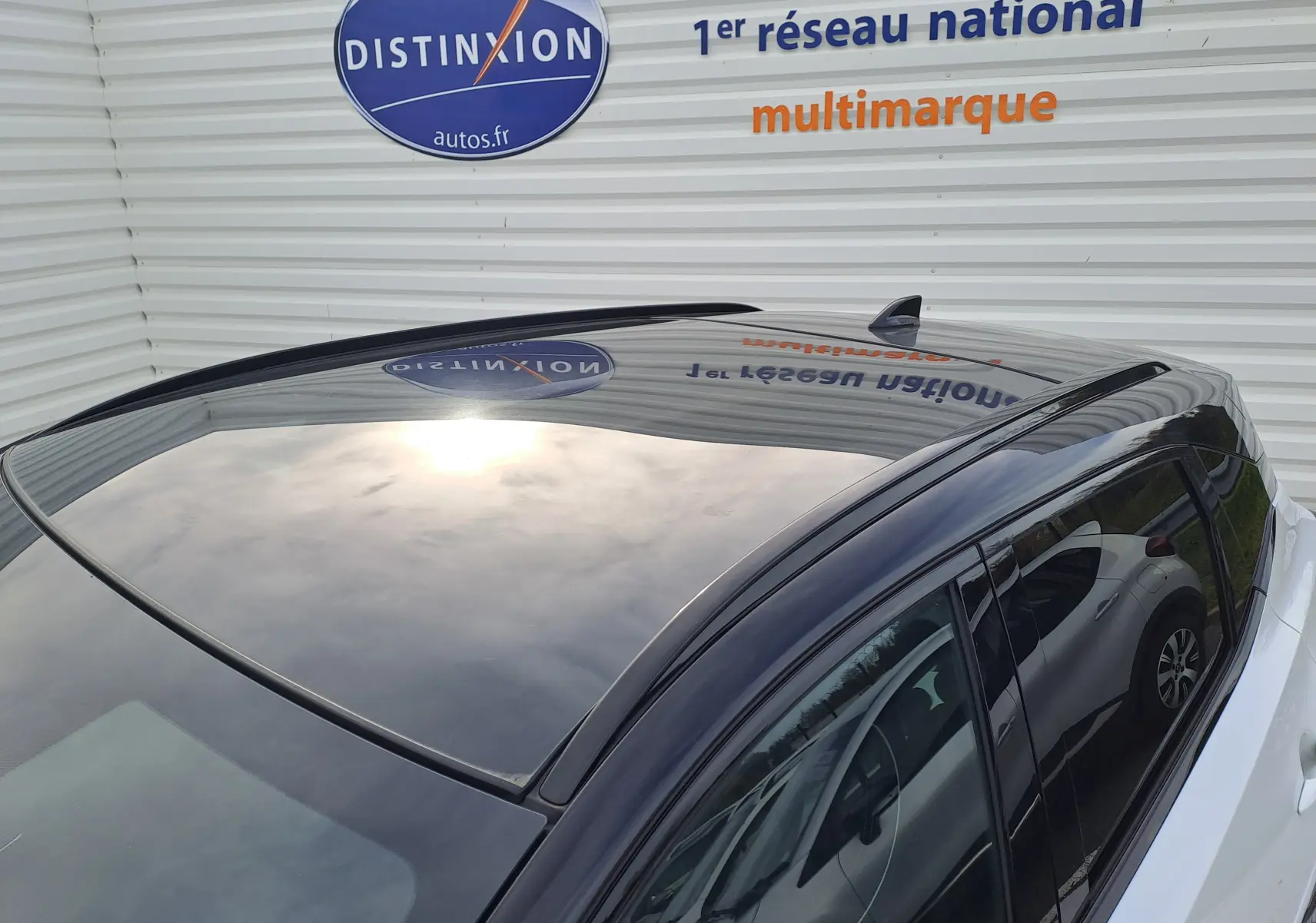 Toit panoramique noir brillant du Nissan Qashqai blanc nacré, vu en plongée depuis l'arrière droit.