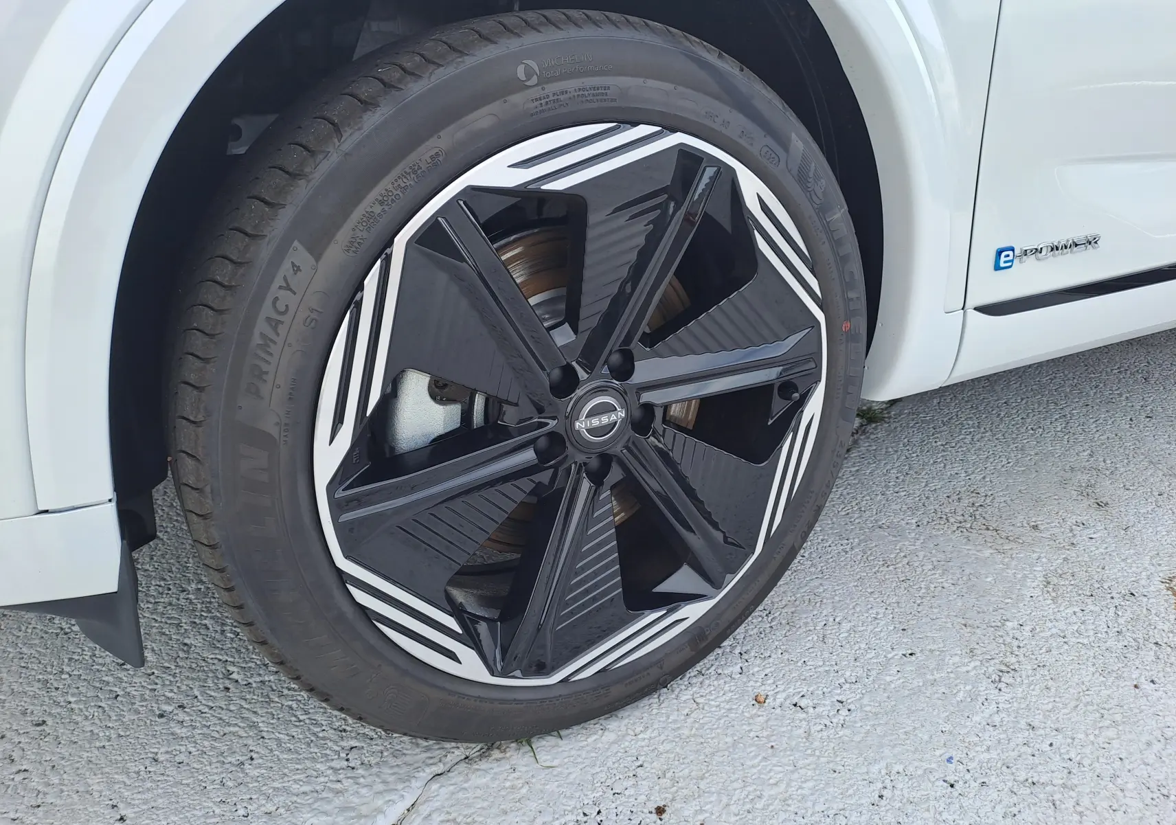 Gros plan sur la roue avant gauche du Nissan Qashqai blanc nacré avec jante noire et blanche au design moderne.