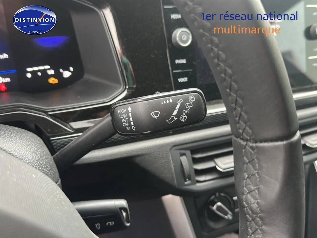 Gros plan sur la commande d’essuie-glace à gauche du volant cuir d’une Volkswagen Polo gris cendre, tableau de bord noir.