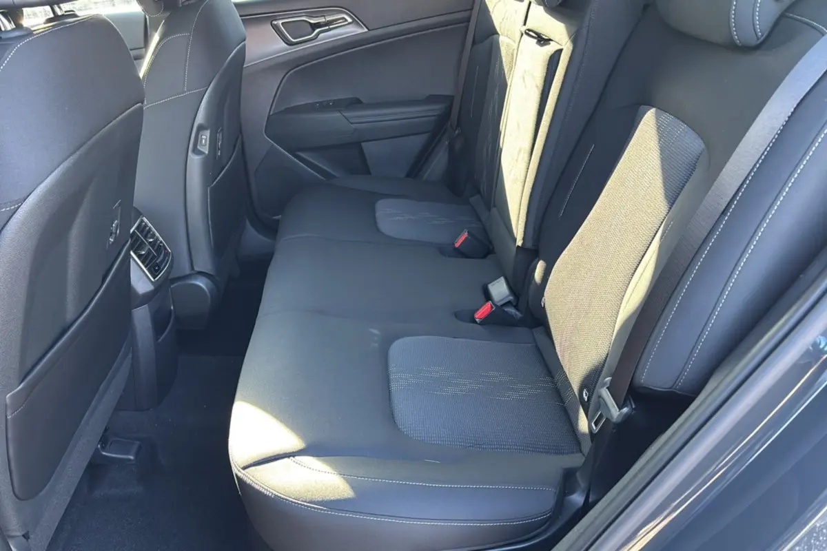 Vue côté droit de la banquette arrière en tissu gris du Kia Sportage 1.6 T-GDI HEV 239 EX avec ceintures et appuie-têtes.