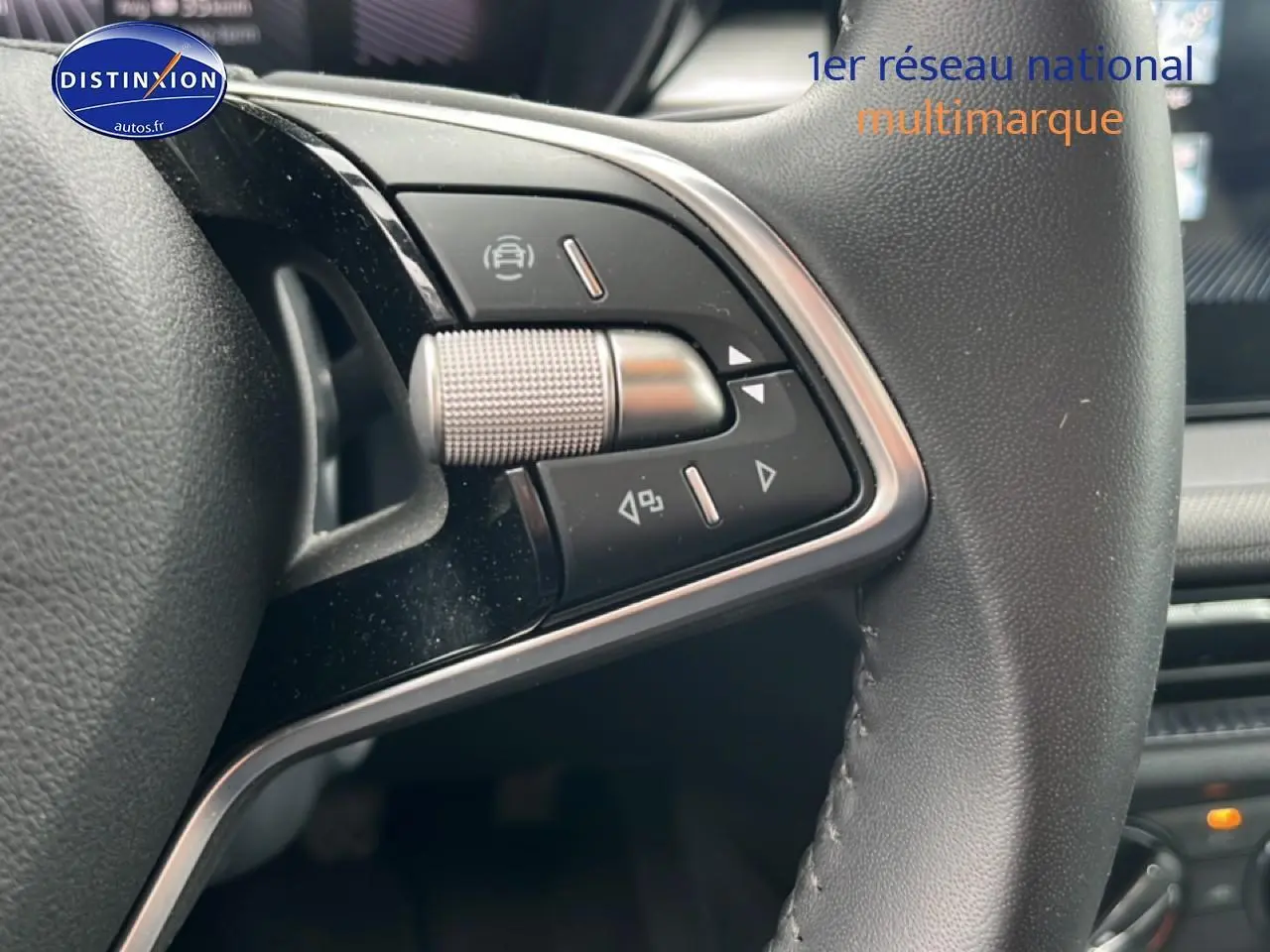 Gros plan sur les commandes multifonctions en cuir du volant de la Skoda Fabia blanche, intérieur moderne.