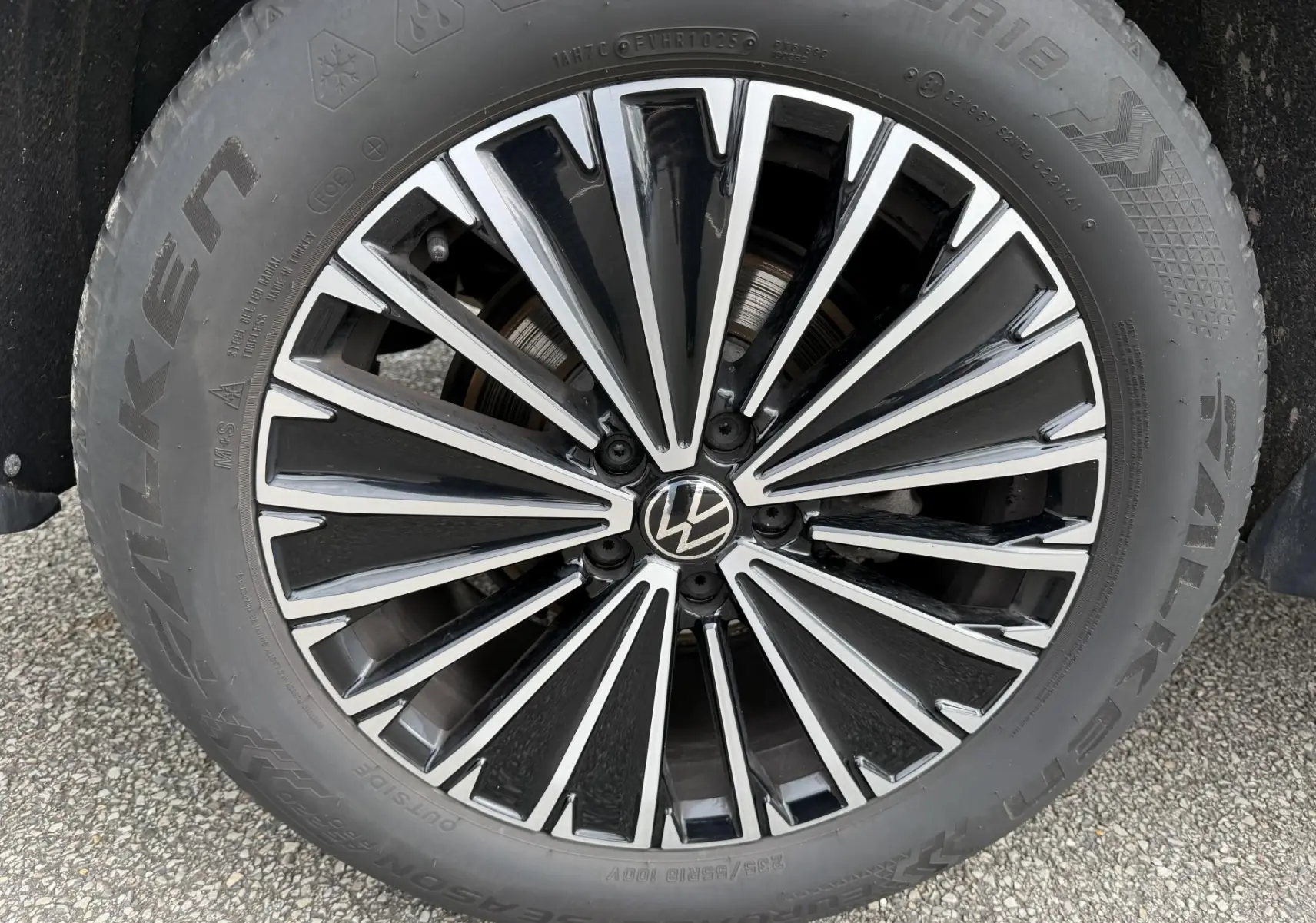 Gros plan sur la jante alliage bicolore noire et argent du Volkswagen Tiguan blanc, mettant en valeur le logo VW central.