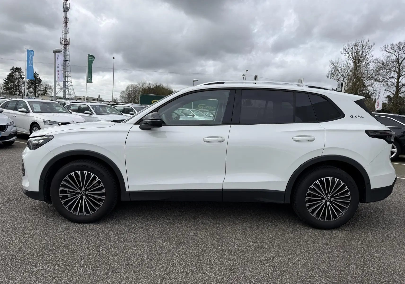 Vue de profil côté gauche d'un Volkswagen Tiguan blanc 2025 avec jantes noires et vitres arrière teintées.